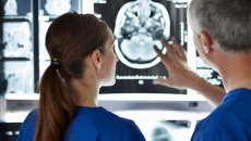 Two healthcare providers looking at a diagnostic image of a brain scan