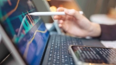 Pen touching a computer screen with financial data