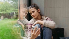 Person sitting by a window while holding a phone