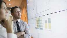 Two people looking at a screen with graphs on it