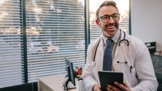 Physician holding a stethoscope and a tablet computer