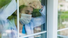 Medical worker leans against window