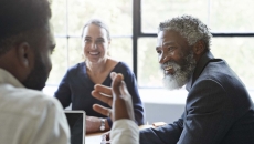 Three business people sitting around a table and talking