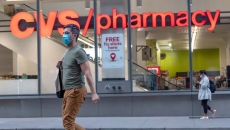 A masked person walking by a CVS pharmacy.