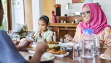 People sitting around a dinner table with food on it