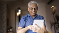 Person wearing a blue shirt and holding a tablet in the living room of a home