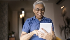 An elderly using a digital tablet at home