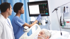 Providers using the new patient monitor next to a bed where a patient is sleeping