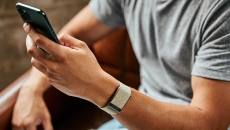 A close up of a man wearing the WHOOP 4.0 on his wrist while using a smartphone