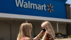 Walmart customer, puts a mask on her daughter outside a Walmart store