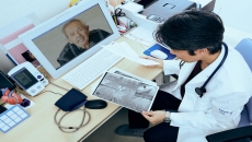 A doctor speaking with a patient using telehealth and looking at imaging results.