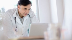 Healthcare provider leaning on a desk and looking at a computer