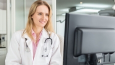 A doctor checking a patient's medical record on a desktop computer