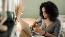 A person sitting at a desk using a laptop.