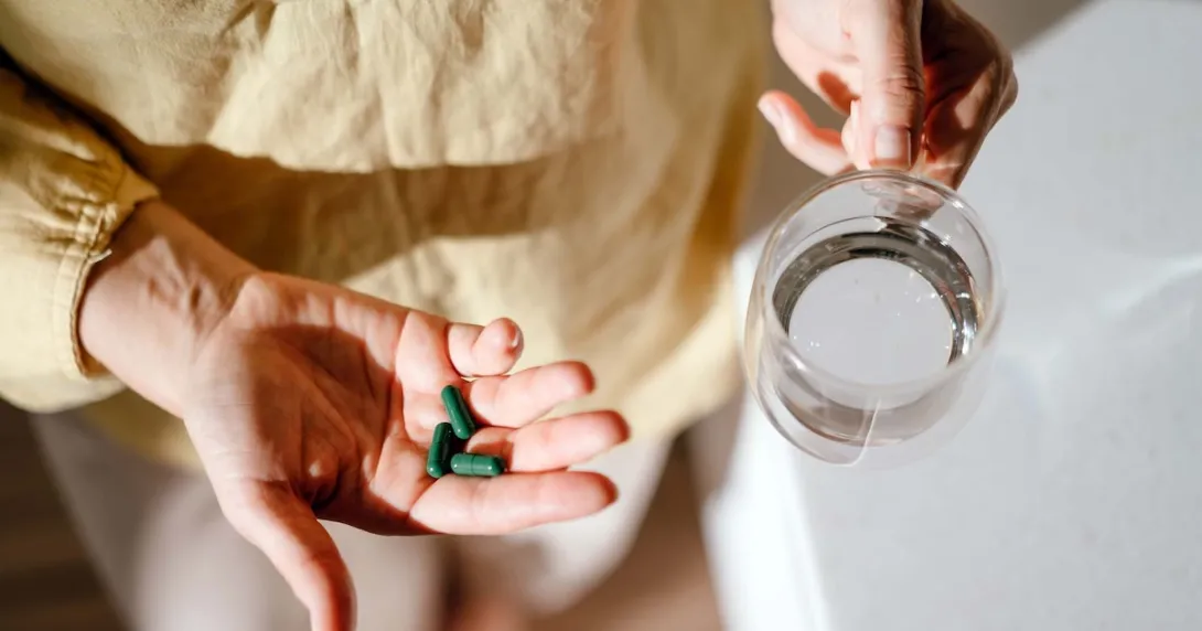 Person holding pills and a glass of water