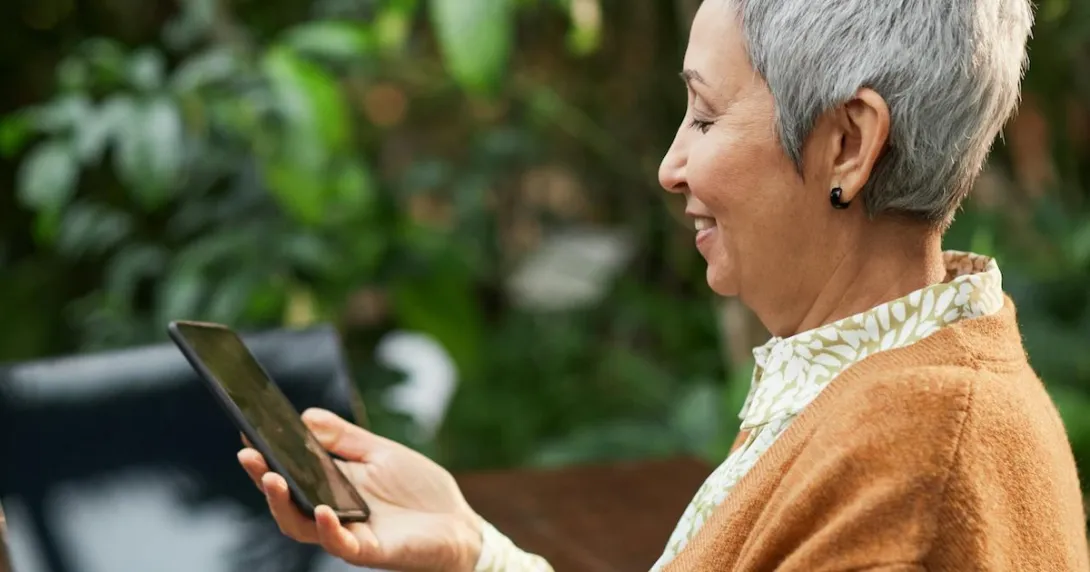 A smiling elderly person using a smartphone
