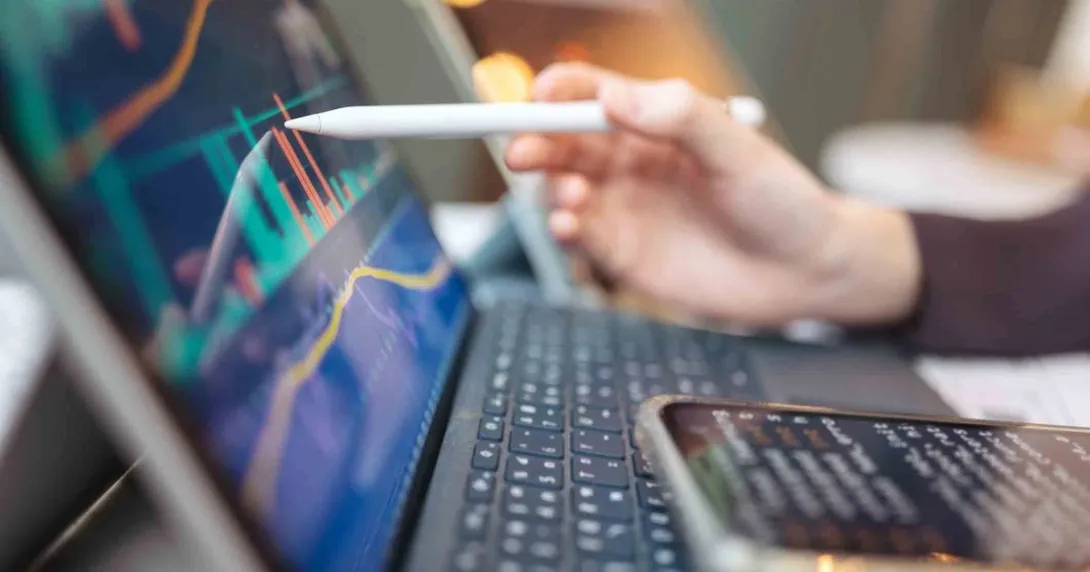 Pen touching a computer screen with financial data