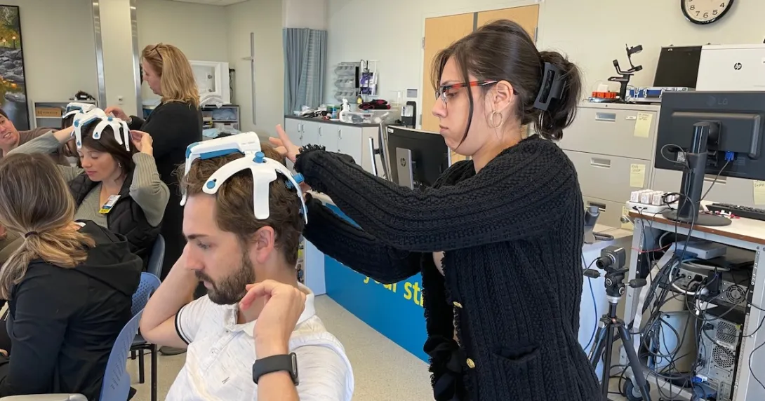 A therapist-in-training putting on the SynPhNe device on a volunteer's head