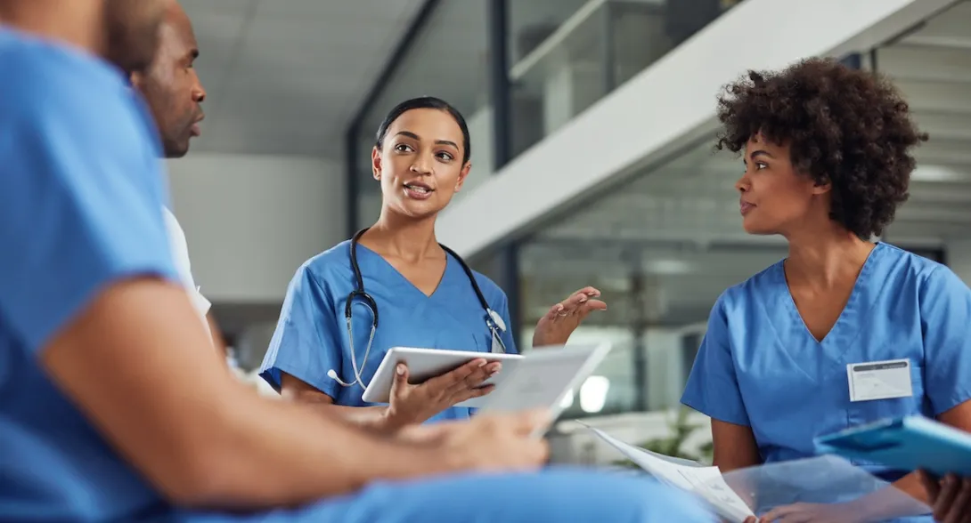 Three healthcare providers sitting in a circle and talking to each other