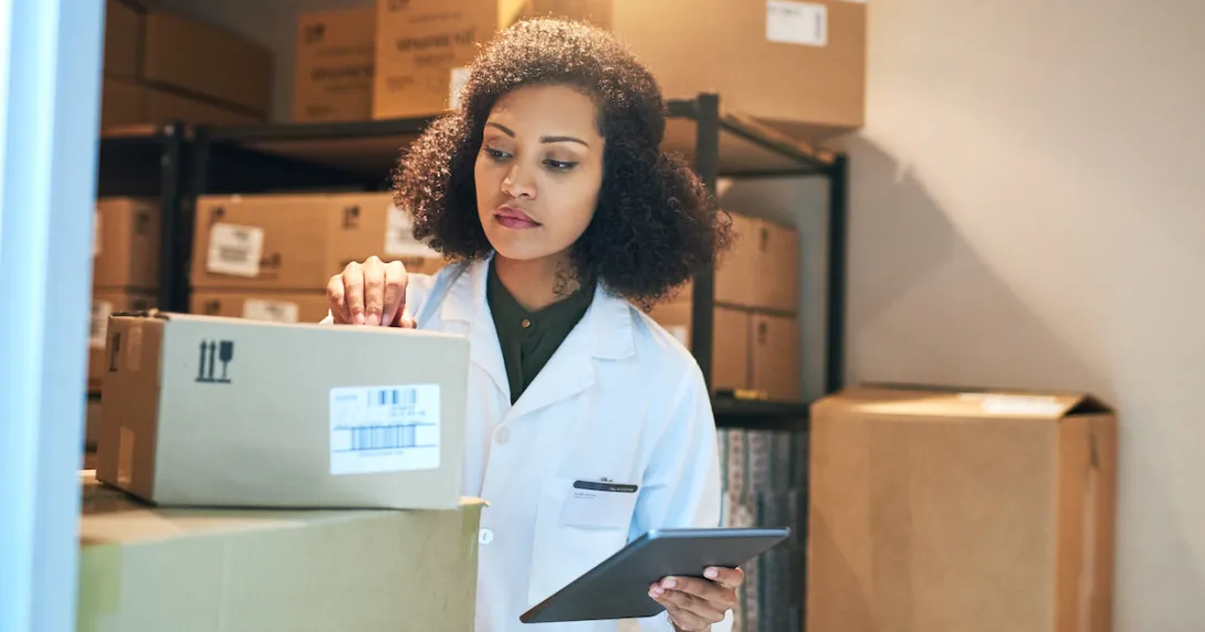 A person using a digital tablet while doing inventory in the storeroom of a pharmacy