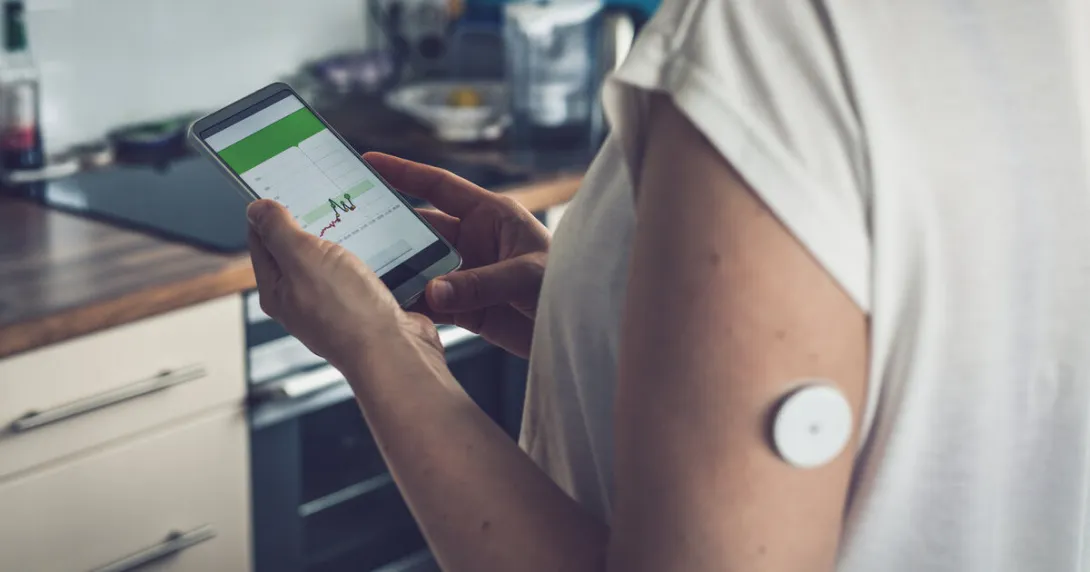 A person wearing a CGM patch checking their blood glucose level on a mobile app