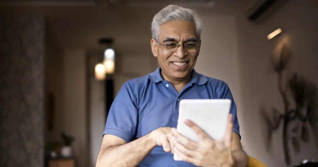 Person in a blue shirt holding a tablet while smiling and looking at the device