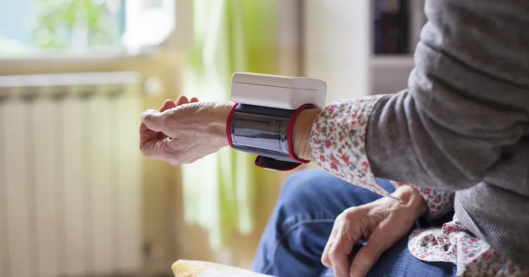 Person sitting on a bed with a wearable on their wrist