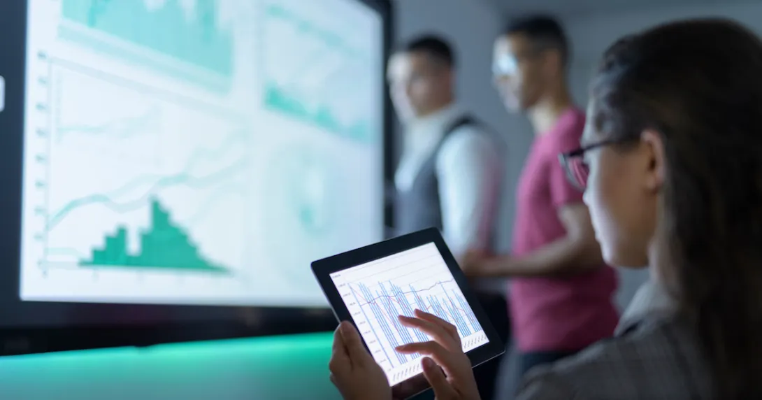 Three people in a room looking at different graphs on separate screens