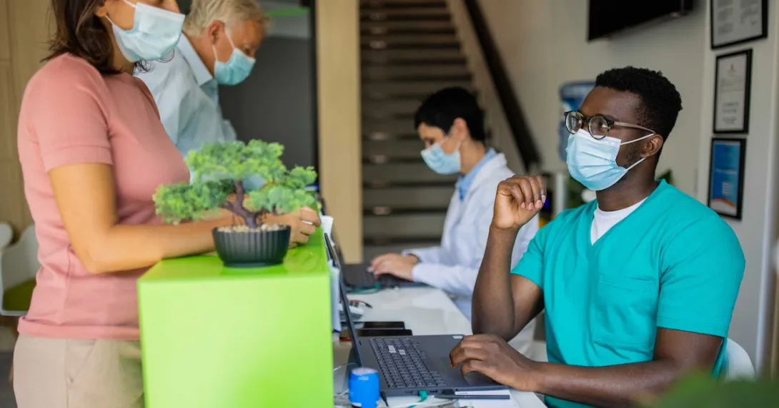 Healthcare providers sitting at a table with two people standing up on the other side