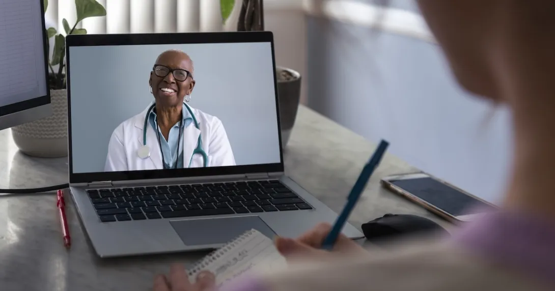Physician interacting remotely with a person via laptop