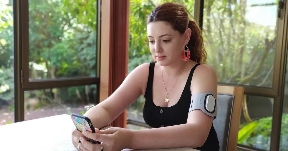 A person wearing an armband with the Theranica device while holding a smartphone.