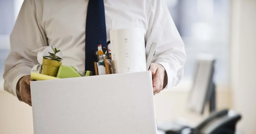 A worker holding a box of his belongings.
