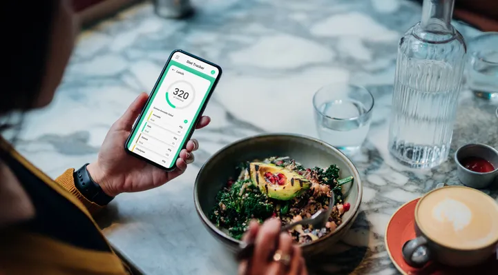 A person using a phone to track the calories in a salad