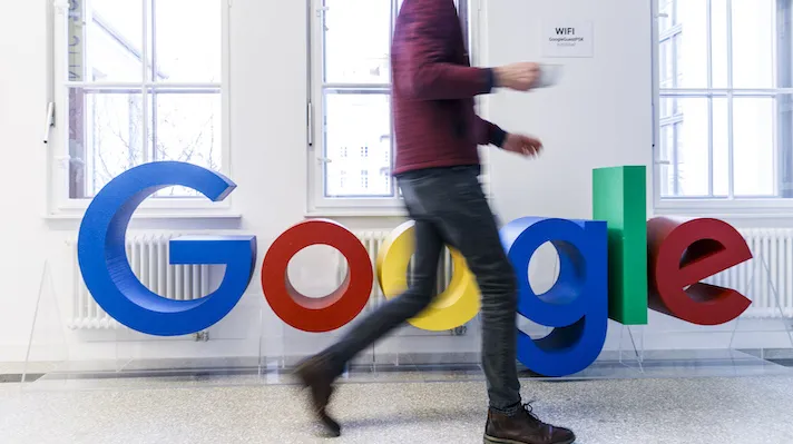 A person walking by the Google logo