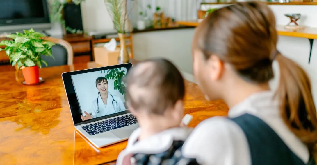 A mother and baby on a video call with a doctor.