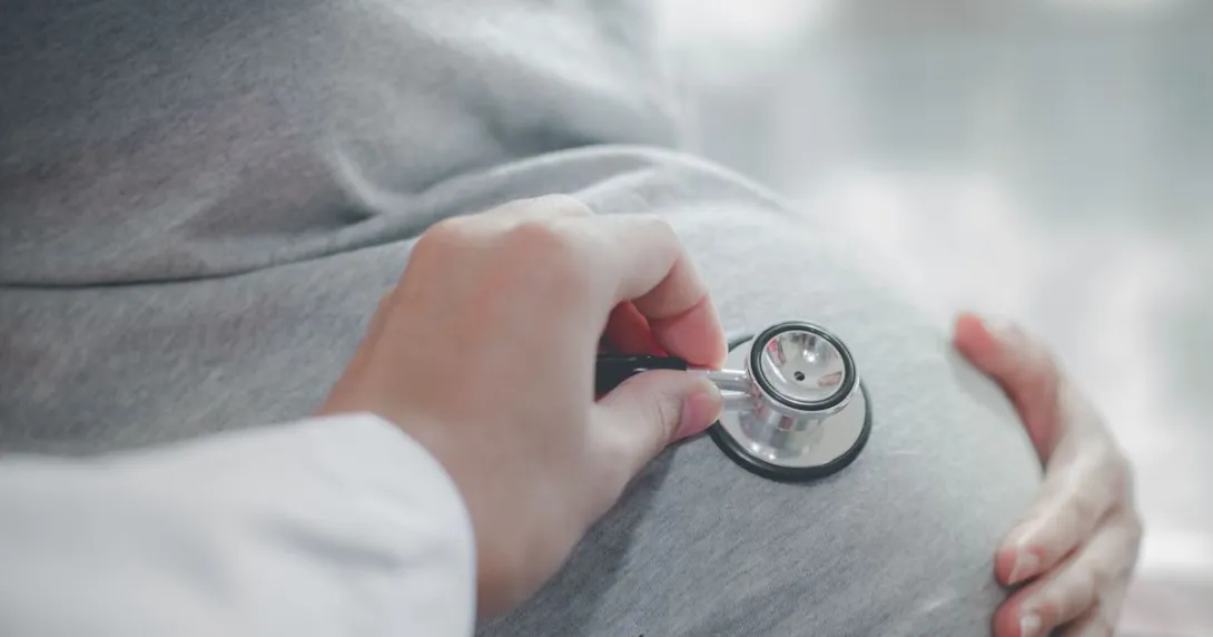 A health professional placing a stethoscope on a pregnant belly