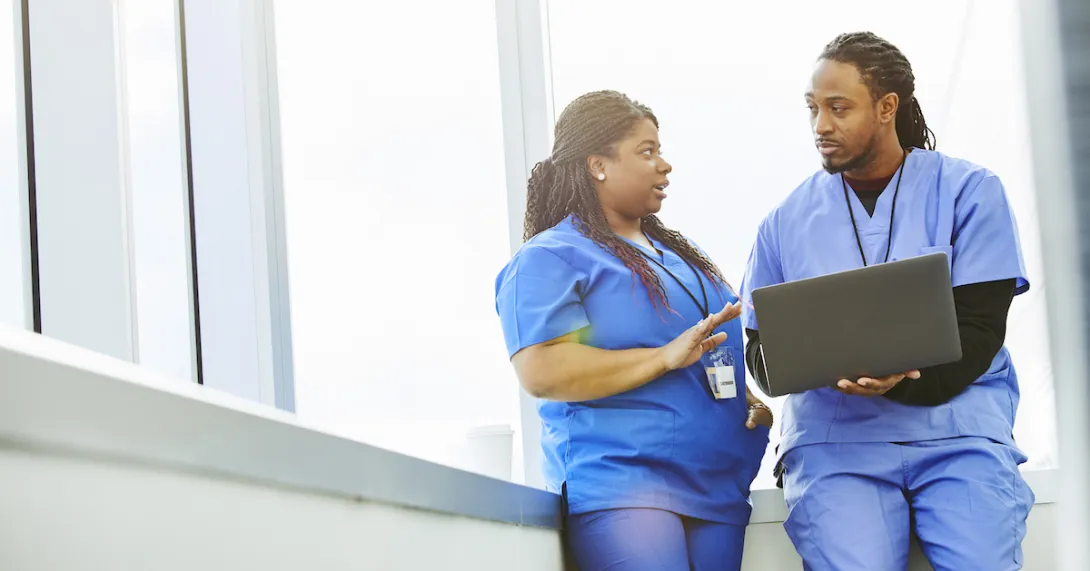 A doctor showing his colleague information on a laptop