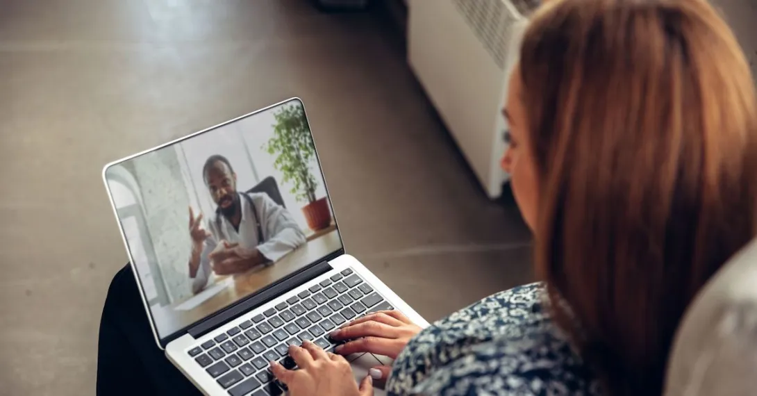 A woman talking to a doctor through a video chat on her laptop