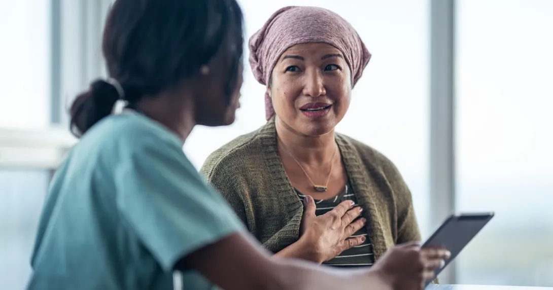 Patient sitting next to a healthcare provider and looking at a tablet