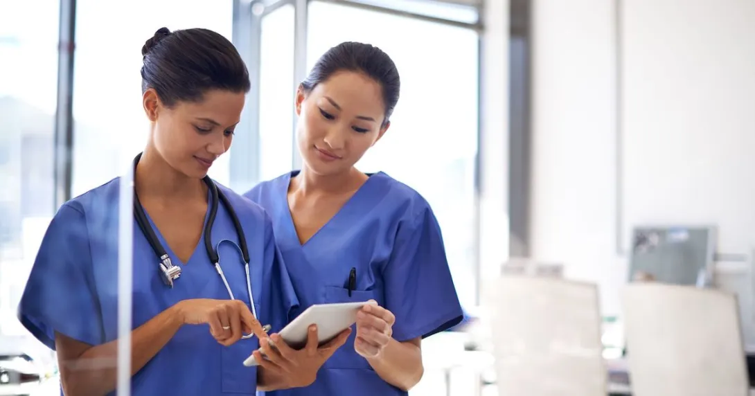 Two healthcare providers standing up while looking at one tablet