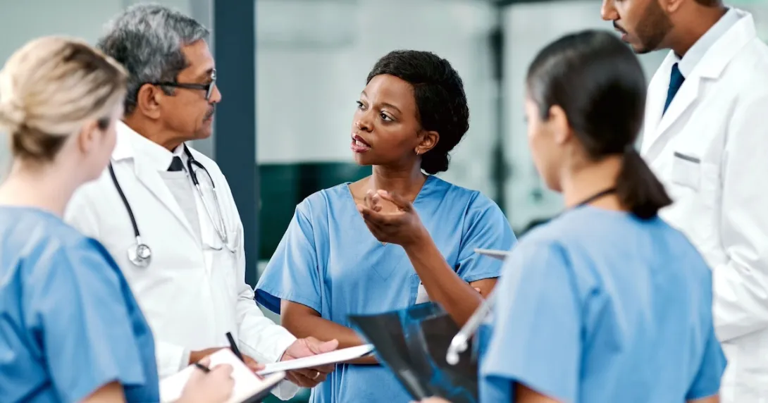Five healthcare providers standing in a circle, talking to each other