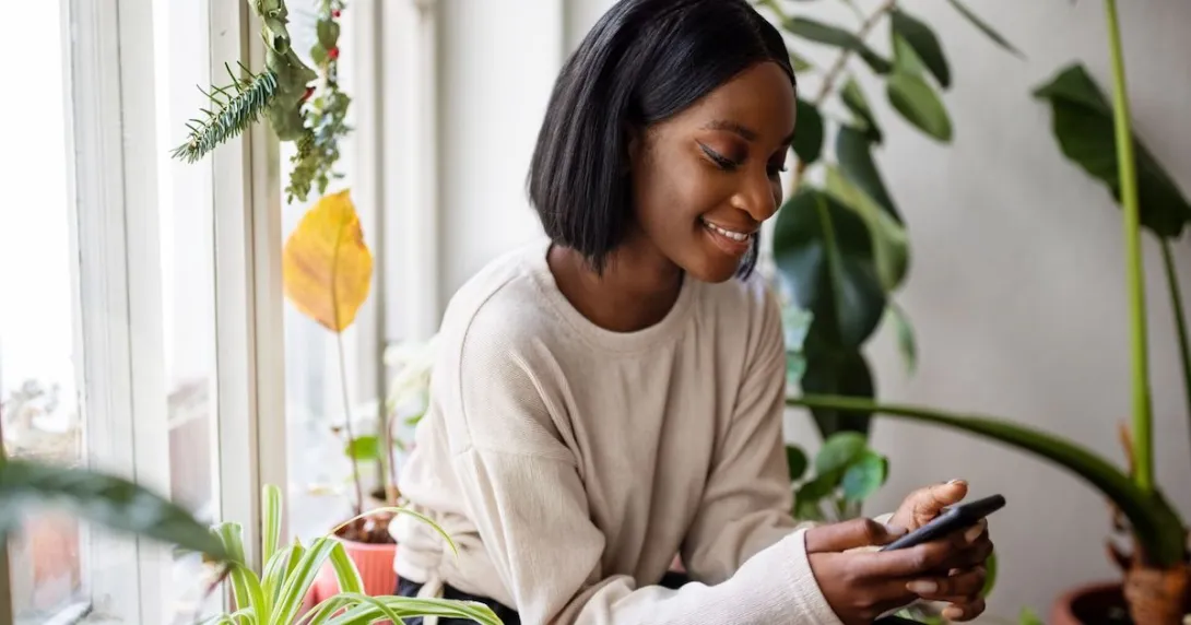 Person sitting in a chair and surrounded by plants while looking at a phone