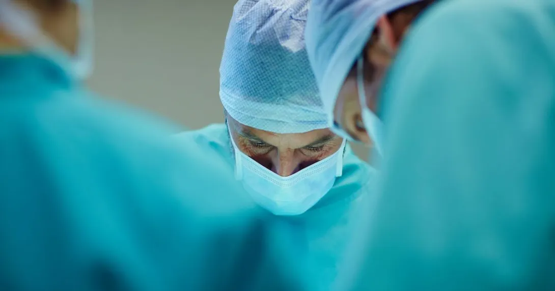 Close up of healthcare providers in scrubs looking down while performing surgery