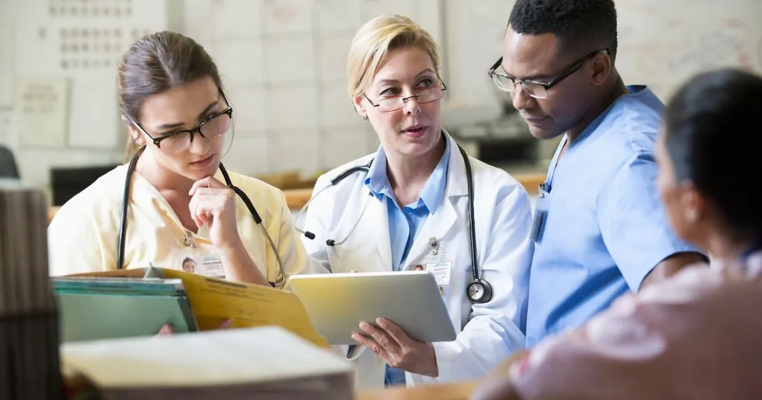 Three healthcare providers sitting together looking at a tablet together