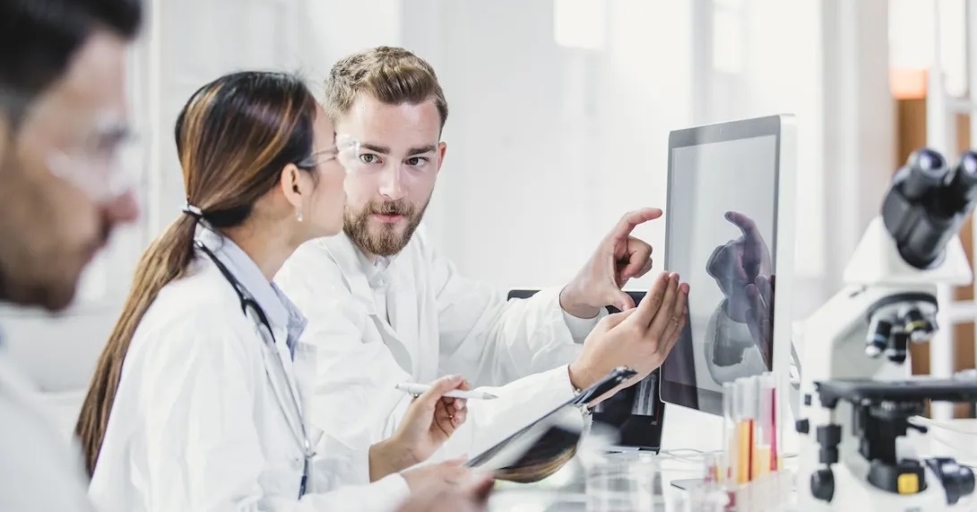 Two people standing in a laboratory looking at a computer