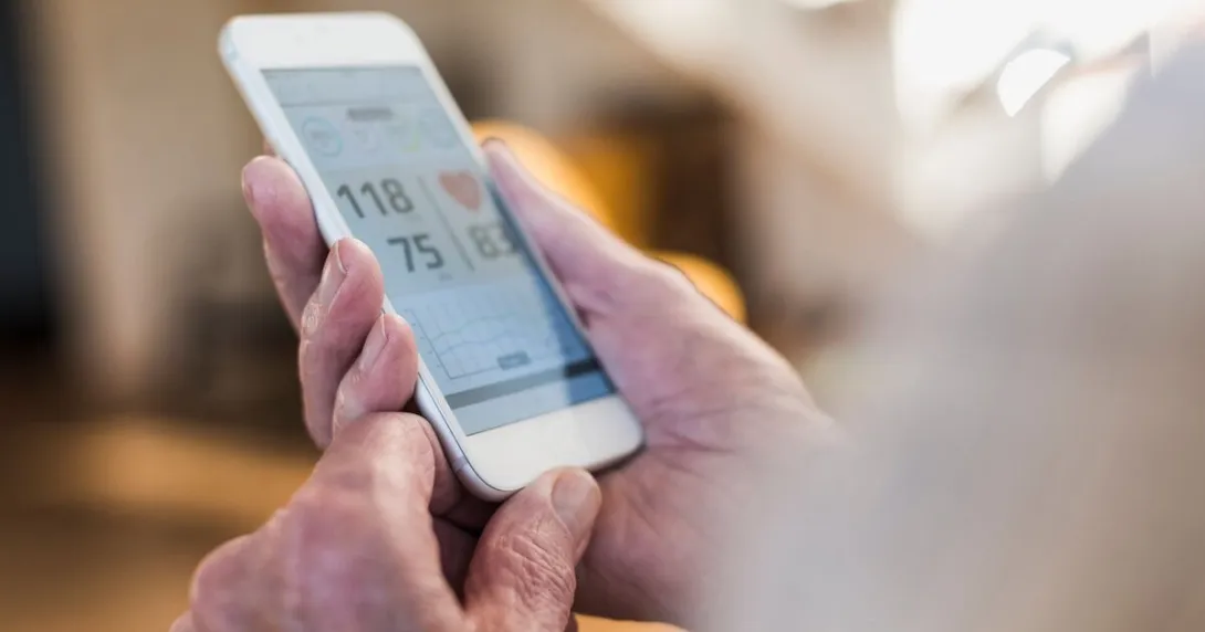 An individual holding a mobile phone showing their heart rate