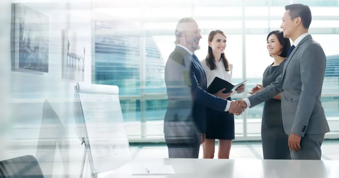 Four people standing a room with two of them shaking hands