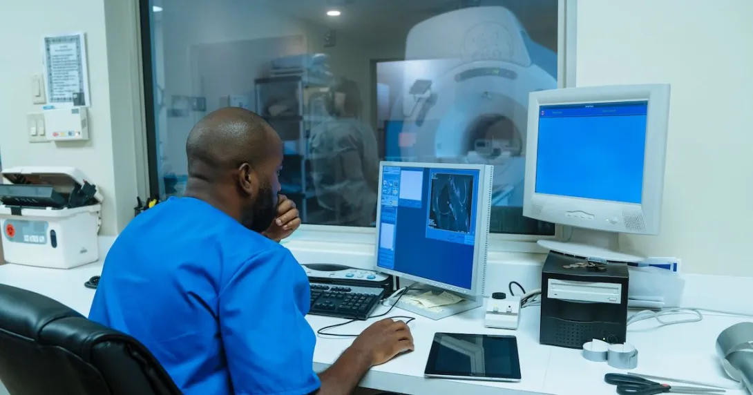 Healthcare provider sitting in a diagnostic imaging room with an MRI machine in the window
