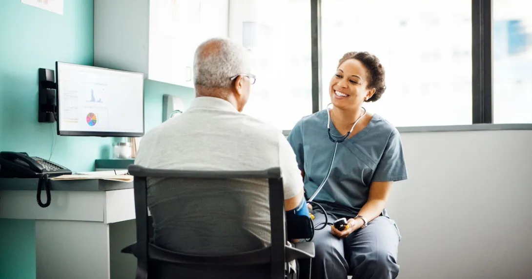 Healthcare provider sitting with a patient near a desk