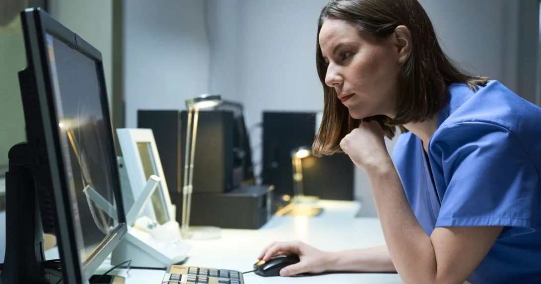 A clinician reading a report from a desktop computer.